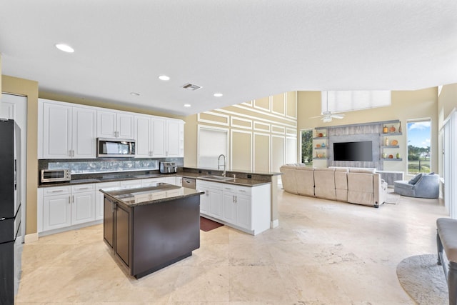 kitchen with a kitchen island, appliances with stainless steel finishes, open floor plan, white cabinetry, and a sink