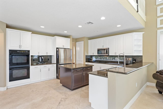 kitchen with a peninsula, white cabinetry, appliances with stainless steel finishes, and open shelves