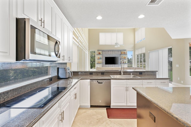 kitchen featuring a ceiling fan, appliances with stainless steel finishes, white cabinets, and a sink