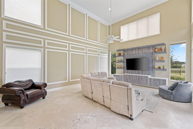 living room with crown molding, a decorative wall, a towering ceiling, and ceiling fan