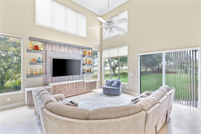 living area featuring a ceiling fan, crown molding, a towering ceiling, and baseboards