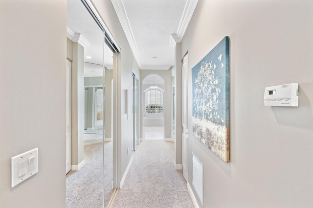 corridor with light carpet, ornamental molding, visible vents, and baseboards