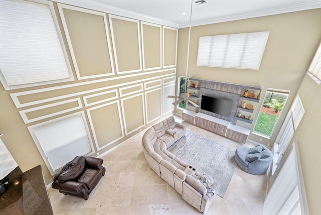 living room with ornamental molding, a fireplace with raised hearth, a decorative wall, and light tile patterned floors