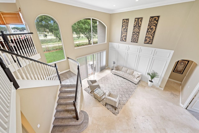 bedroom featuring a towering ceiling, baseboards, arched walkways, and crown molding