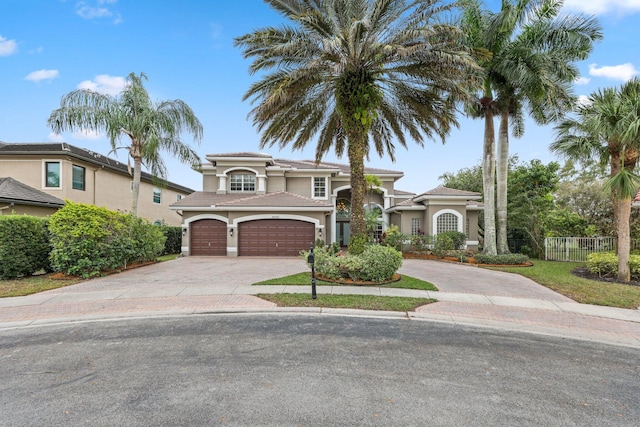 mediterranean / spanish home with a garage, decorative driveway, a tile roof, and stucco siding