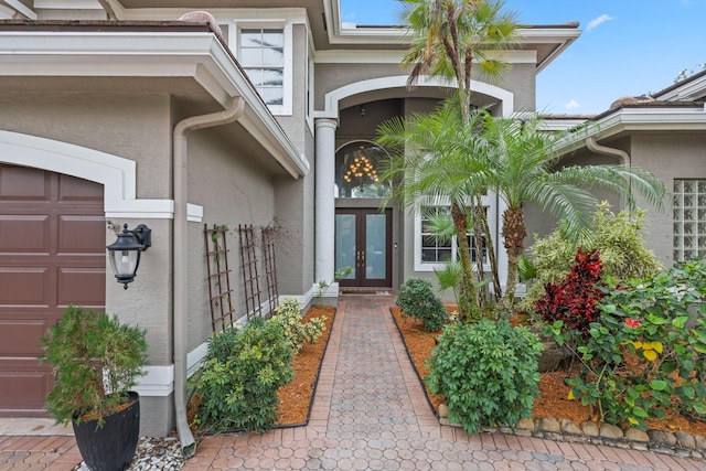 view of exterior entry featuring a garage, stucco siding, and french doors