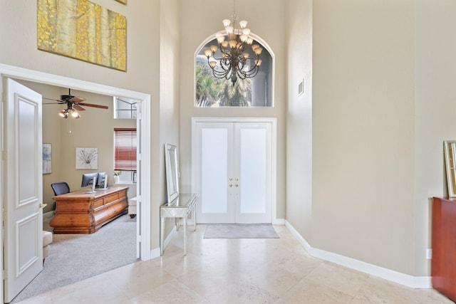 foyer featuring light carpet, baseboards, a high ceiling, french doors, and a chandelier