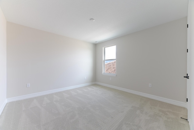 spare room with light carpet and baseboards