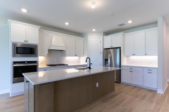 kitchen featuring stainless steel appliances, a sink, visible vents, white cabinetry, and custom exhaust hood