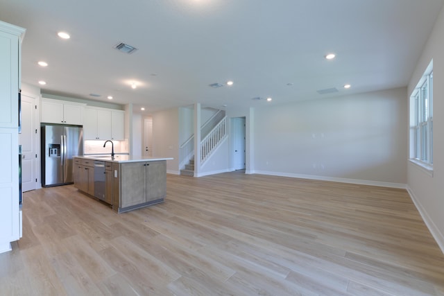 kitchen featuring a kitchen island with sink, stainless steel appliances, visible vents, light wood-style floors, and open floor plan