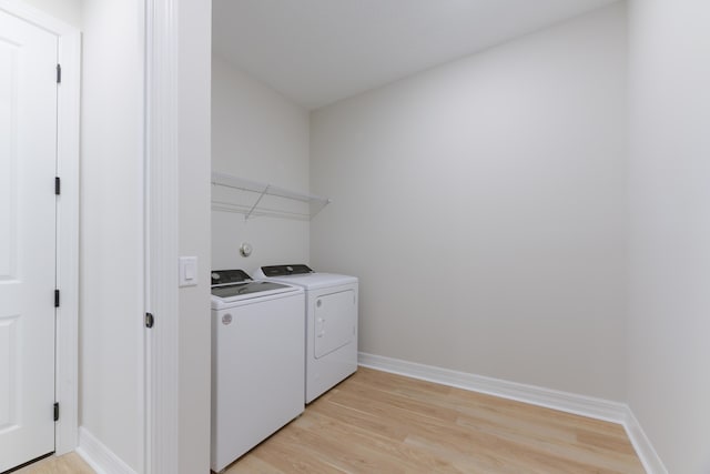 clothes washing area featuring baseboards, laundry area, light wood-type flooring, and washer and dryer