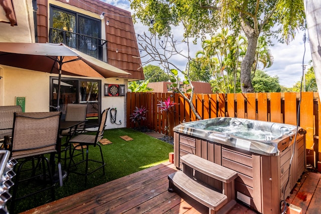 wooden deck with a hot tub, a fenced backyard, outdoor dining area, and a yard