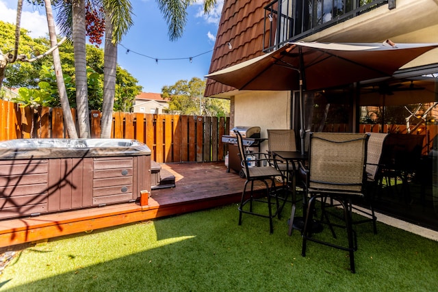 deck featuring a lawn, area for grilling, fence, and a hot tub