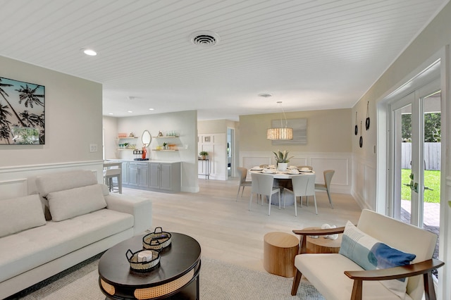 living room featuring a decorative wall, a wainscoted wall, recessed lighting, visible vents, and light wood finished floors