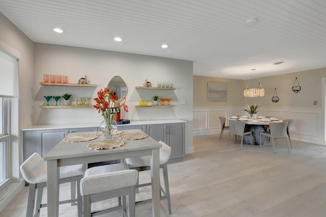 dining area with light wood-type flooring, a wainscoted wall, and recessed lighting