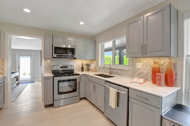 kitchen with stainless steel appliances, gray cabinets, a healthy amount of sunlight, and a sink