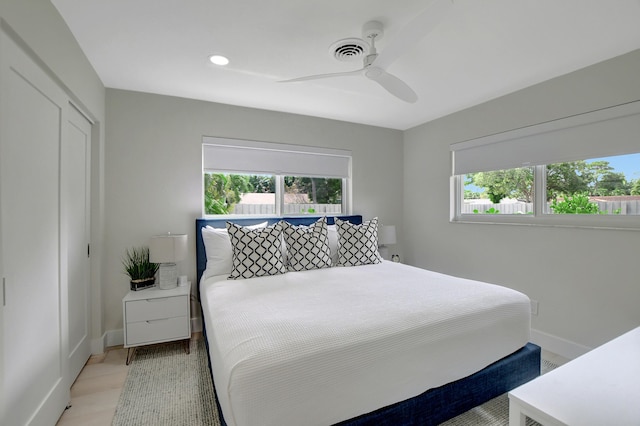 bedroom with a ceiling fan, multiple windows, visible vents, and baseboards