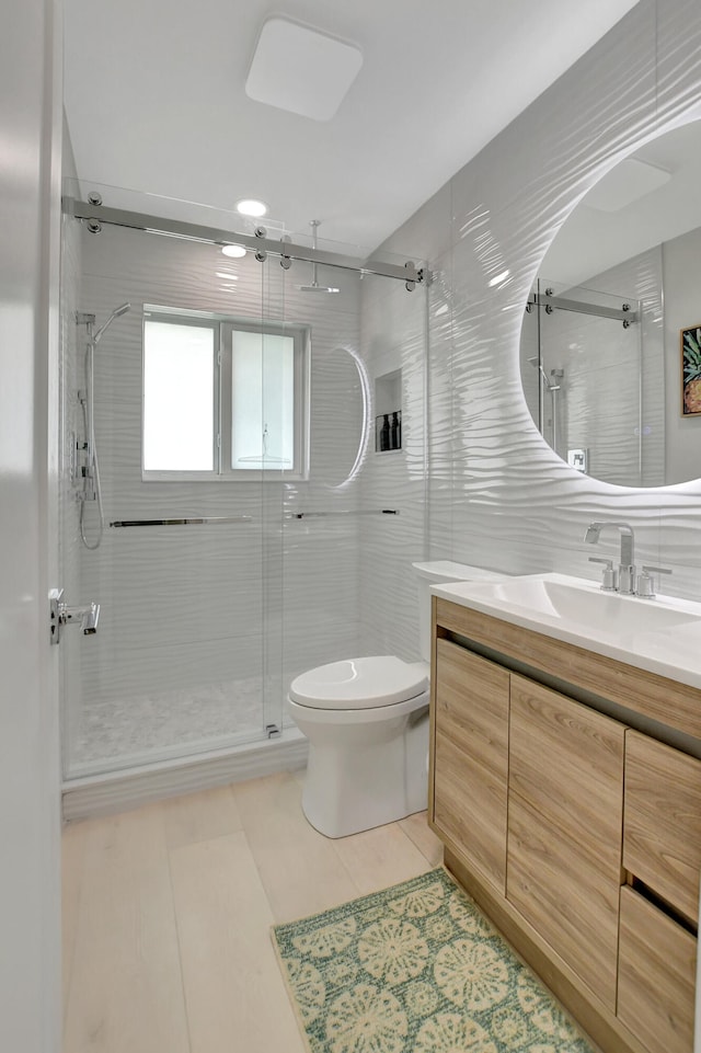 bathroom featuring toilet, a stall shower, tile walls, and vanity