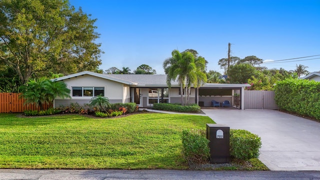 ranch-style home featuring a front lawn, fence, an attached carport, and concrete driveway