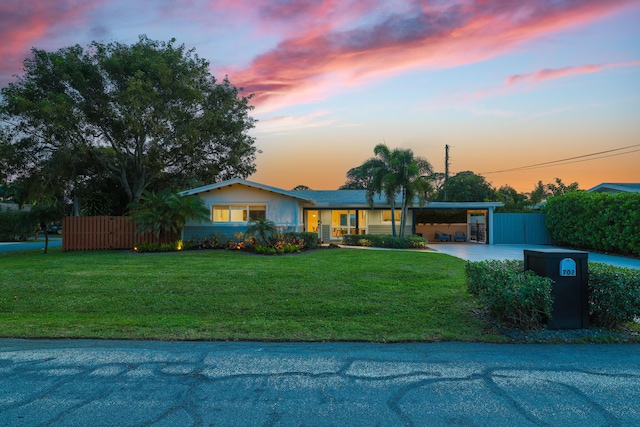 view of front of property with a yard, driveway, a carport, and fence