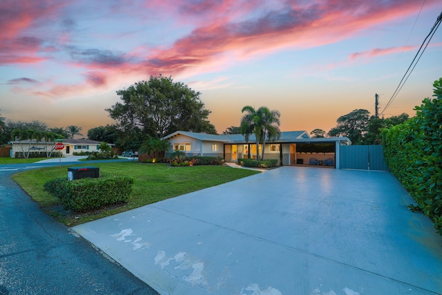 ranch-style house featuring driveway, an attached carport, and a front yard