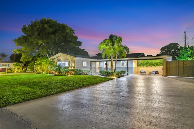 view of front of house featuring fence, an attached carport, concrete driveway, and a front yard