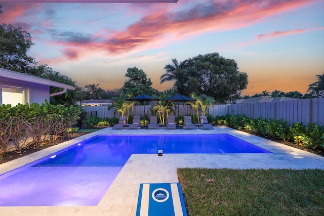 pool at dusk with a fenced in pool, a fenced backyard, and a patio