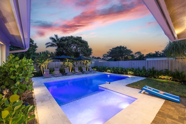 pool at dusk with a fenced backyard, a fenced in pool, and a patio