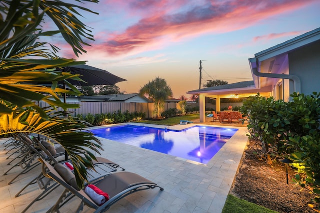 pool at dusk with a patio area, a fenced backyard, and a fenced in pool