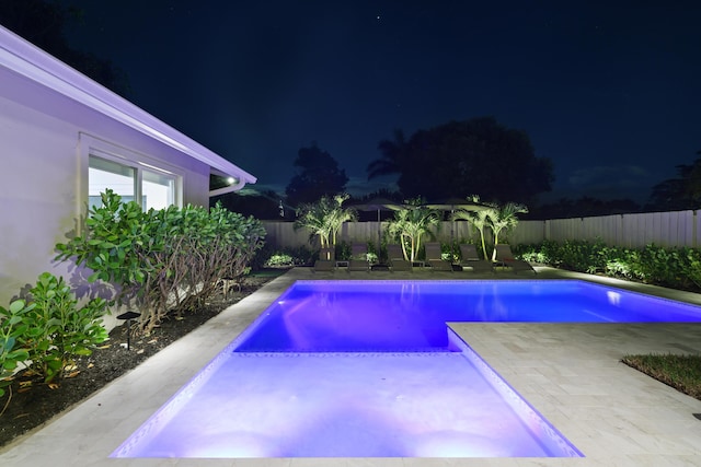 pool at night with a patio, a fenced backyard, and a fenced in pool