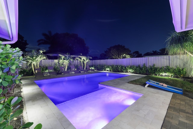 pool at twilight with a patio area, a fenced backyard, and a fenced in pool