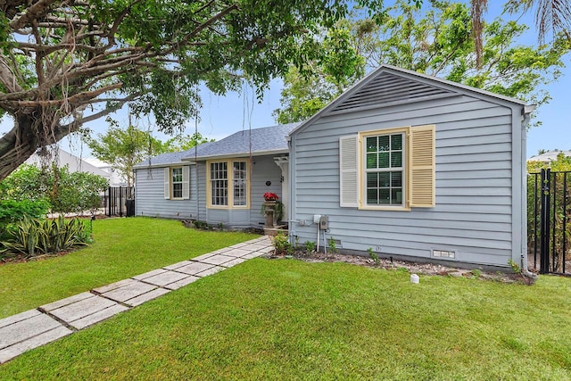 ranch-style home featuring a shingled roof, a front yard, crawl space, and fence