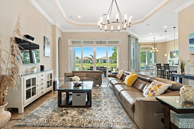 living area featuring a tray ceiling, crown molding, arched walkways, and a notable chandelier