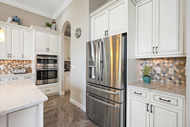 kitchen with arched walkways, stainless steel appliances, ornamental molding, and decorative backsplash