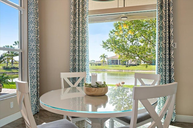 dining area featuring a water view and baseboards