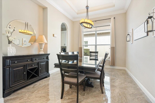 dining area with marble finish floor, ornamental molding, a raised ceiling, and baseboards