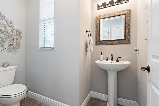 half bathroom featuring toilet and baseboards