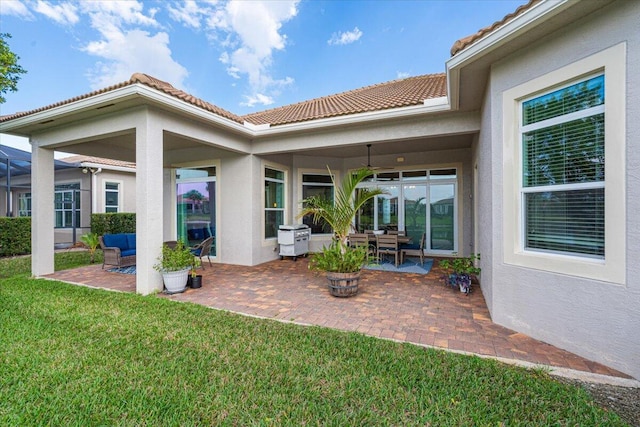 back of property featuring a yard, a tiled roof, a patio area, and stucco siding