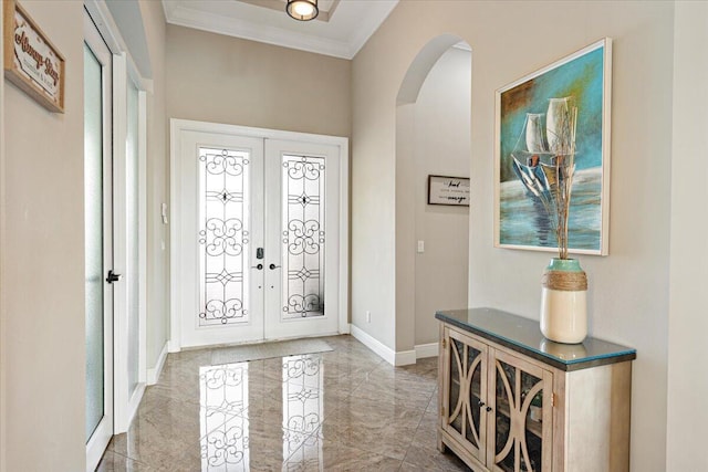 foyer entrance featuring arched walkways, french doors, ornamental molding, and baseboards