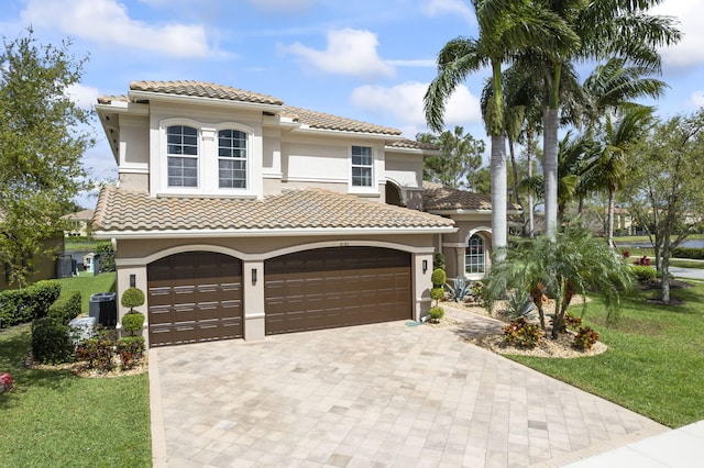 mediterranean / spanish-style home with cooling unit, a tiled roof, decorative driveway, stucco siding, and a front yard