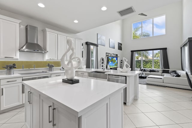 kitchen with visible vents, stainless steel dishwasher, a sink, wall chimney range hood, and black electric cooktop