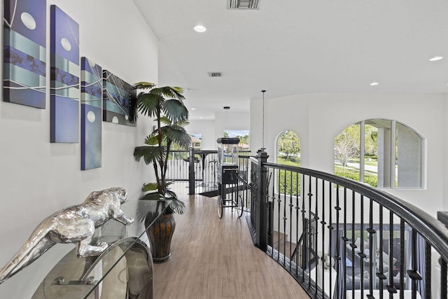 hallway featuring a healthy amount of sunlight, visible vents, wood finished floors, and an upstairs landing