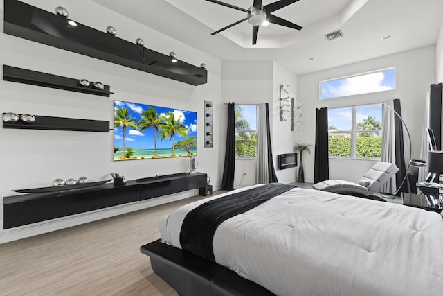 bedroom featuring a raised ceiling, visible vents, ceiling fan, and wood finished floors