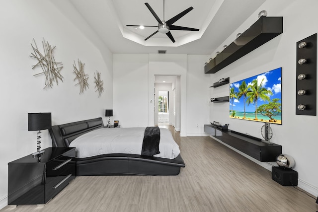 bedroom featuring baseboards, visible vents, a ceiling fan, wood finished floors, and a tray ceiling