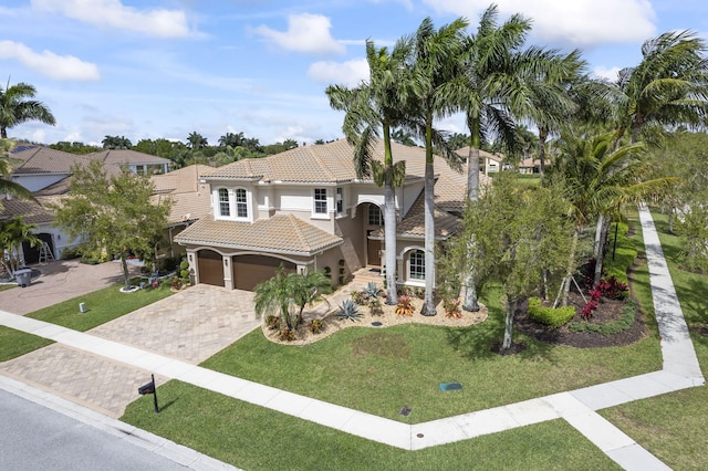 mediterranean / spanish-style home with a tile roof, a front lawn, decorative driveway, and stucco siding