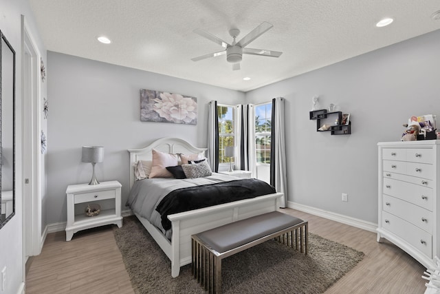 bedroom featuring a textured ceiling, recessed lighting, light wood-type flooring, and baseboards