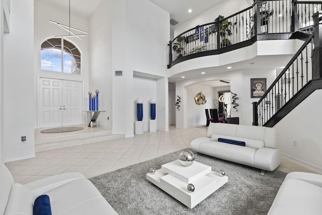 tiled living area featuring recessed lighting, a high ceiling, baseboards, stairs, and an inviting chandelier