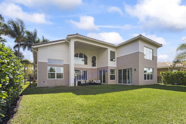 rear view of property featuring a yard, fence, and stucco siding