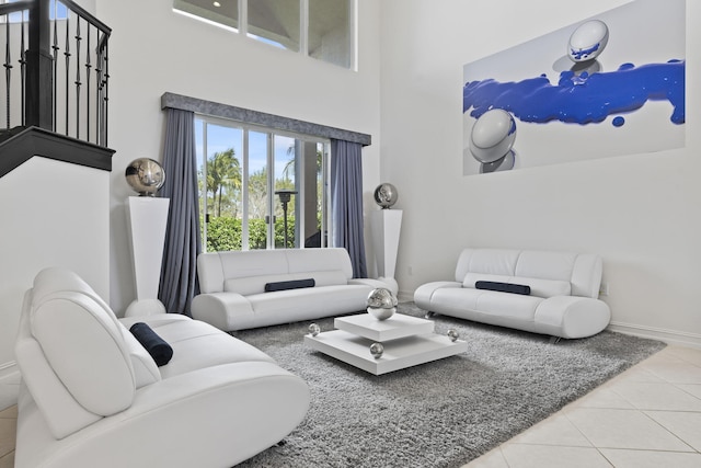 living area with tile patterned flooring, baseboards, and a high ceiling