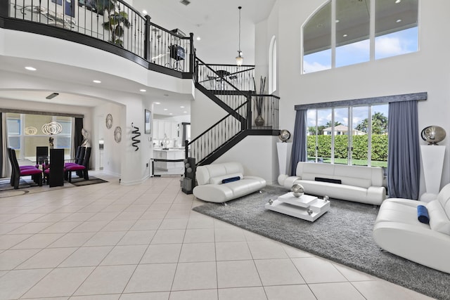 living room with recessed lighting, tile patterned floors, a high ceiling, baseboards, and stairs